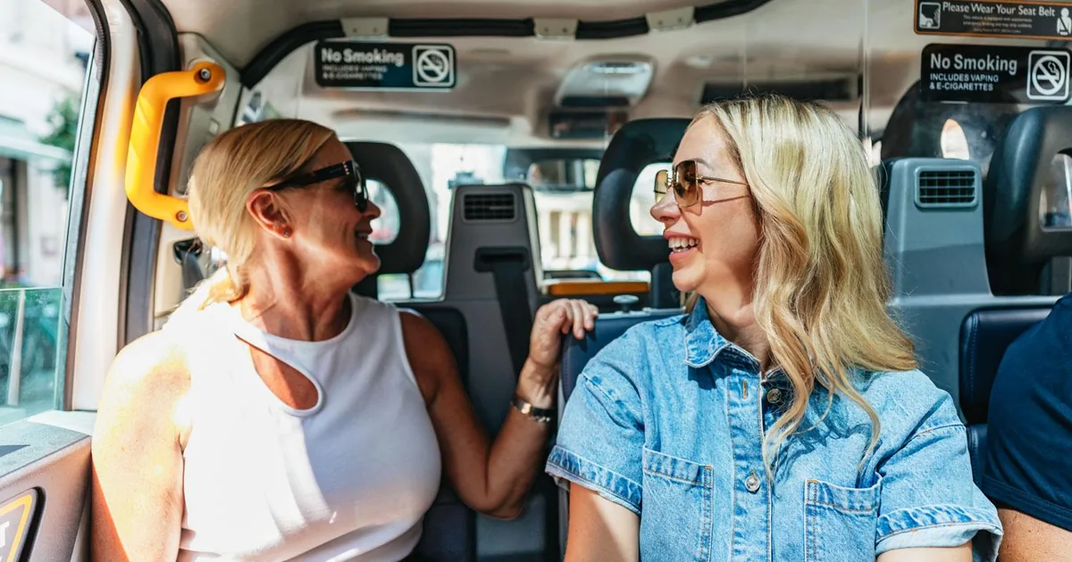 Two guests talking on the rear seats of a London taxi during a private cab tour